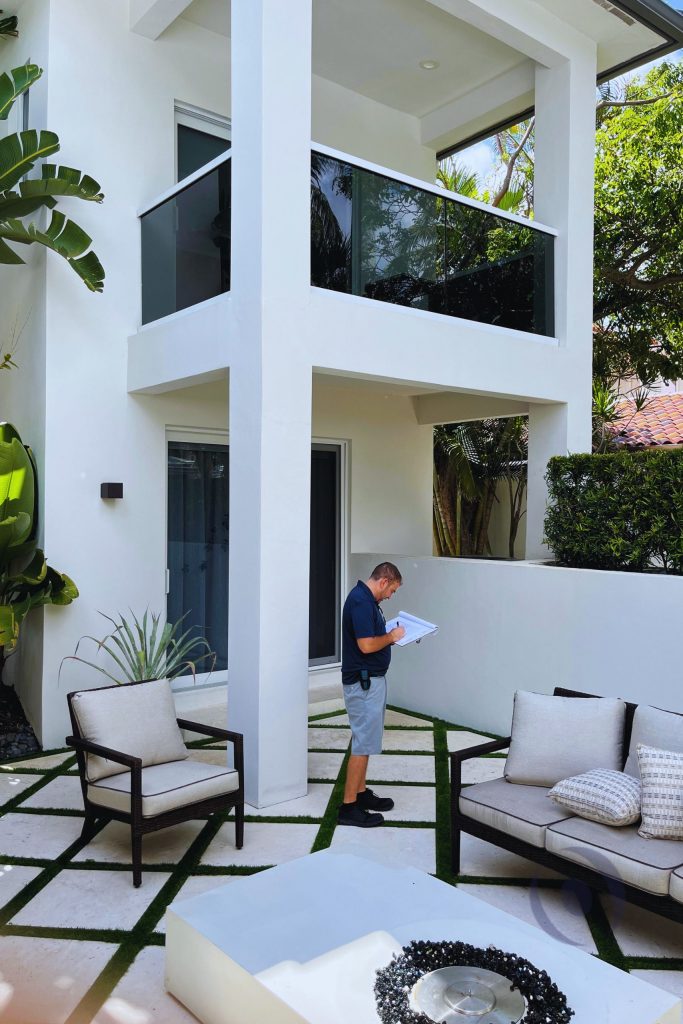 Structural engineer conducting residential inspection at modern courtyard, reviewing structural elements and documenting site conditions