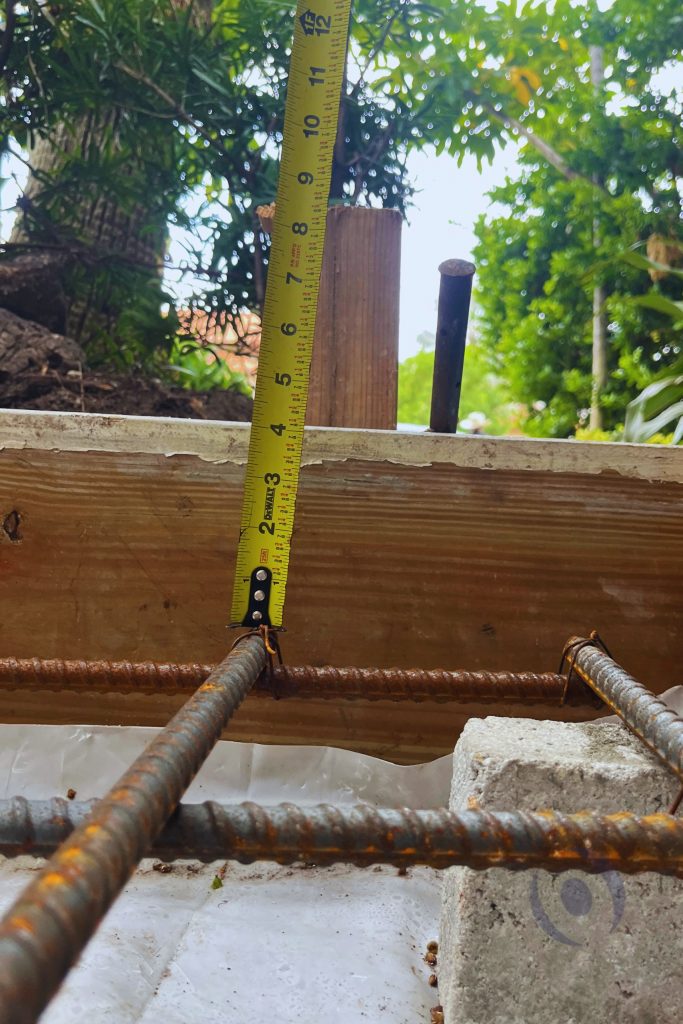 Close-up of reinforced concrete beam formwork with rebar placement and measurement verification before concrete pour