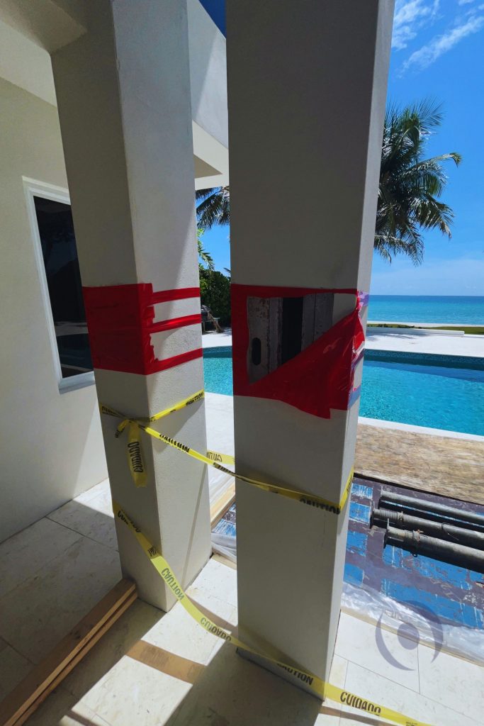 Structural column under inspection with exposed connection detail and safety markings at residential construction site