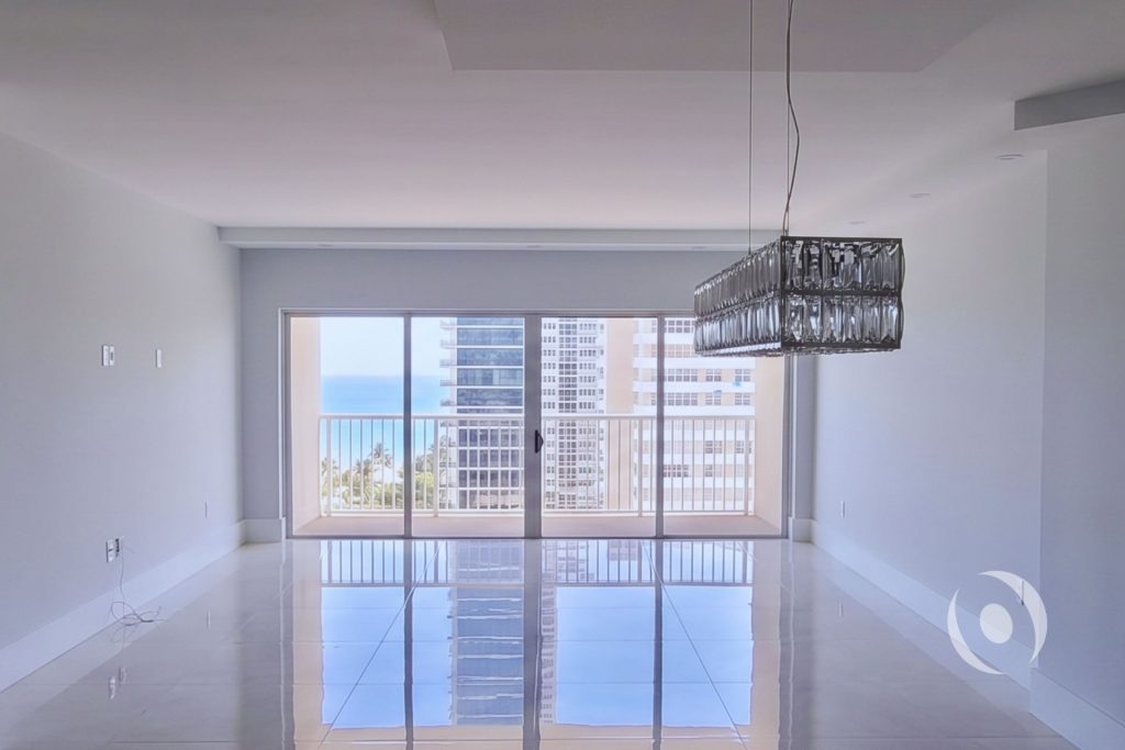 Renovated dining area with crystal chandelier engineered lighting large format porcelain tile and ocean view in completed high-rise condo renovation Hallandale Beach Florida