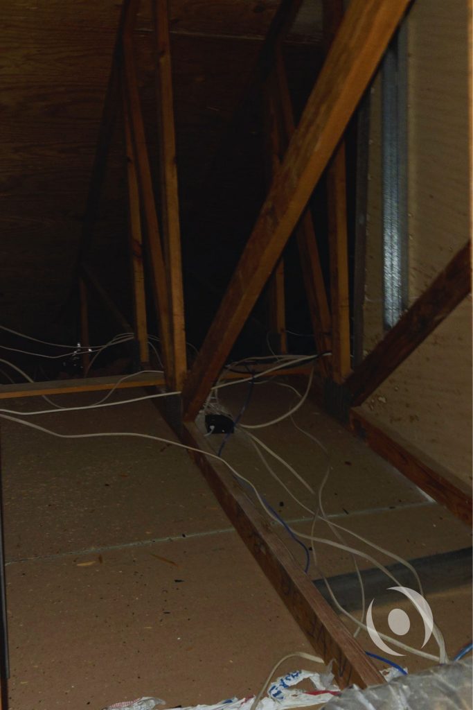 Attic inspection revealing existing roof truss structure and unorganized electrical wiring conditions documented by NOHMIS engineers during pre-design site assessment in Boca Raton, Florida