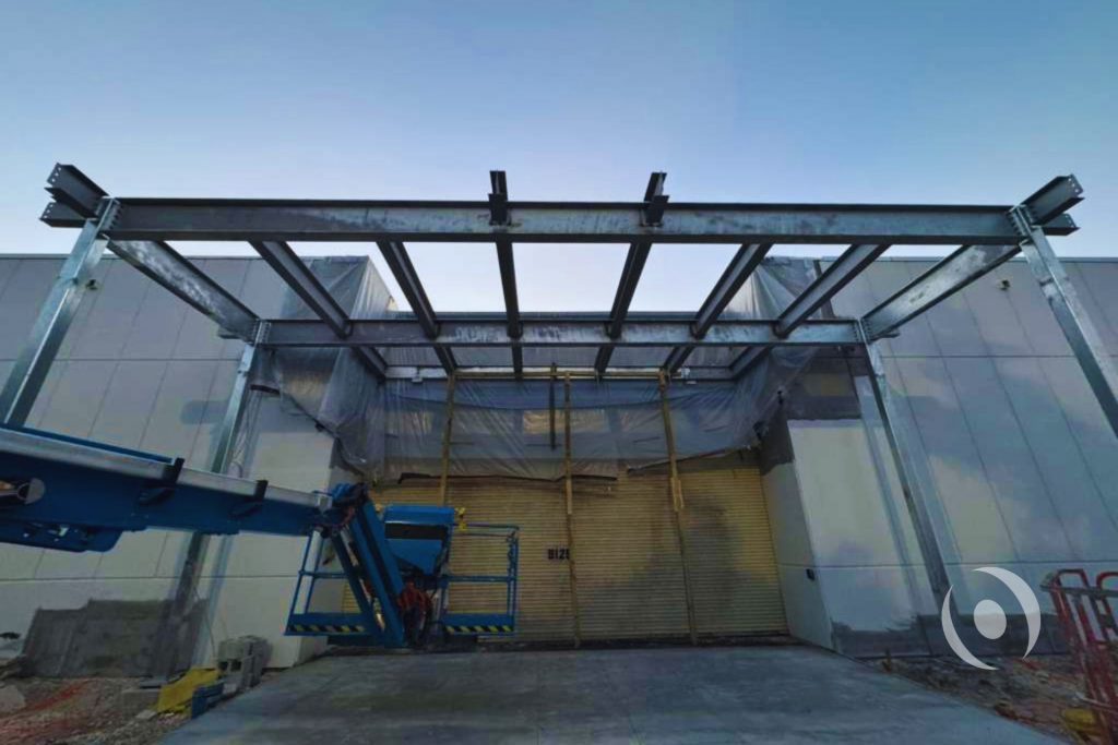 Commercial canopy steel framing during construction phase showing wide-flange girders and HSS columns before cladding — structural engineering by NOHMIS, Broward County, FL