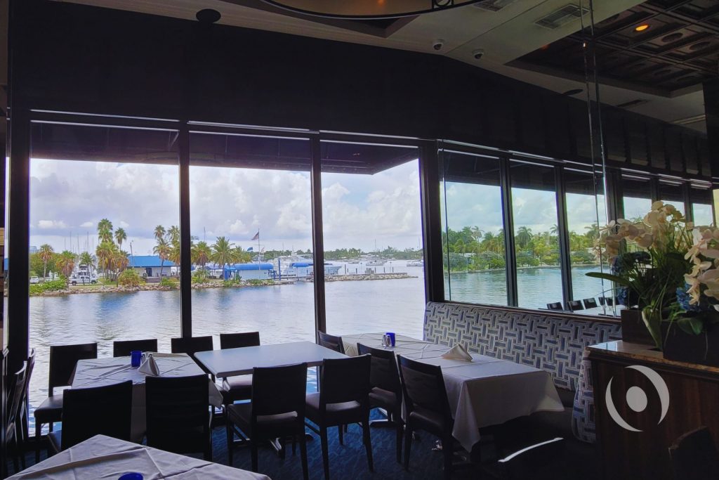 Interior dining room of commercial waterfront restaurant in Hollywood, Florida overlooking the Stranahan River, showing the occupied building that remained fully operational context during NOHMIS structural engineering and concrete restoration work