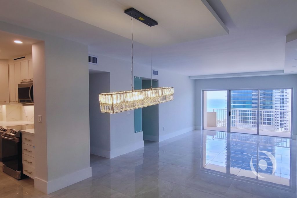 Completed high-rise condominium renovation in Hallandale Beach showing redesigned kitchen glass office door lit crystal chandelier dropped ceiling and Atlantic Ocean view engineered by NOHMIS