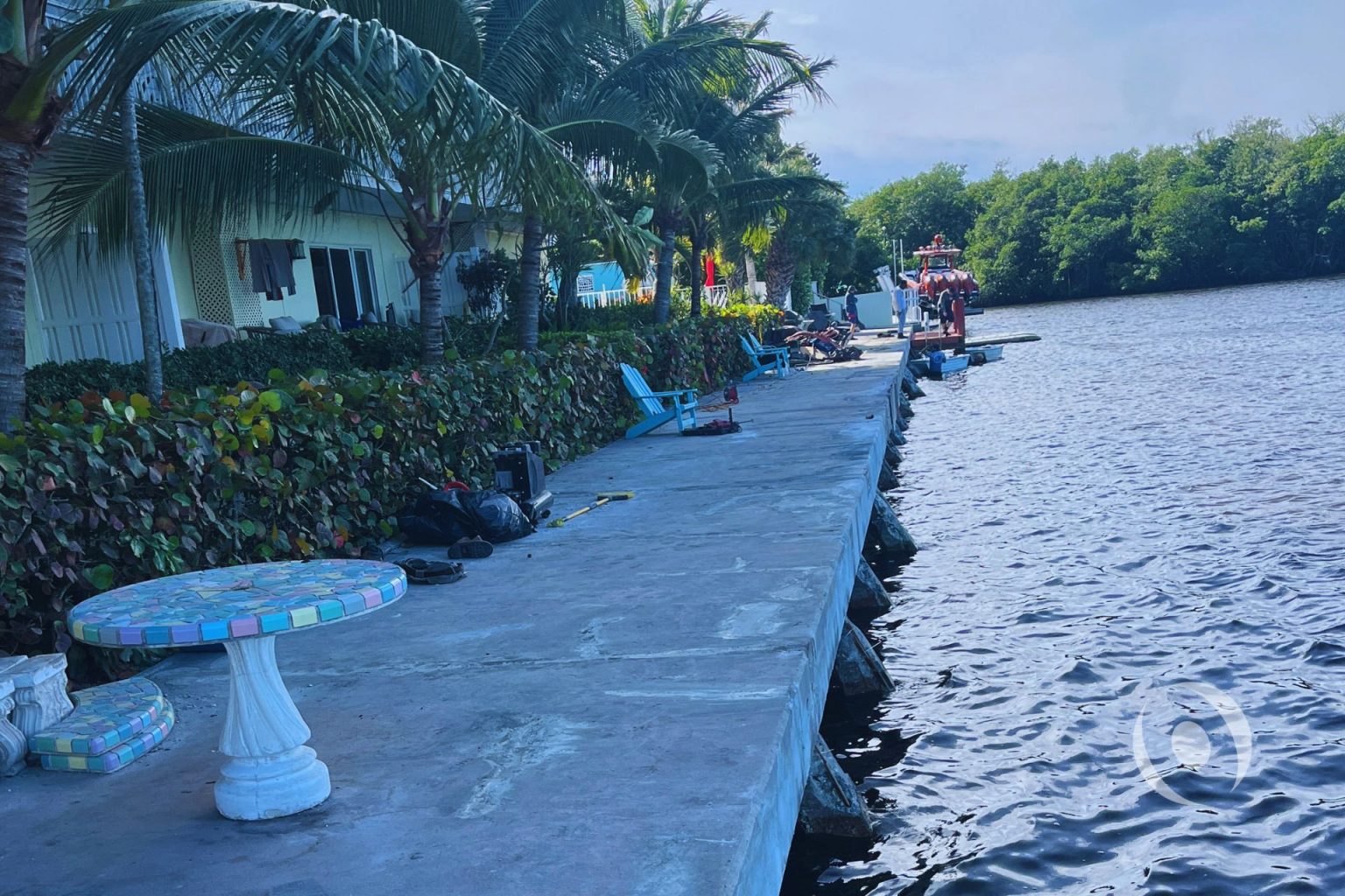 Completed seawall cap repair along a South Florida residential waterfront property with marine construction crew on site, showing restored concrete surface and rip-rap toe protection