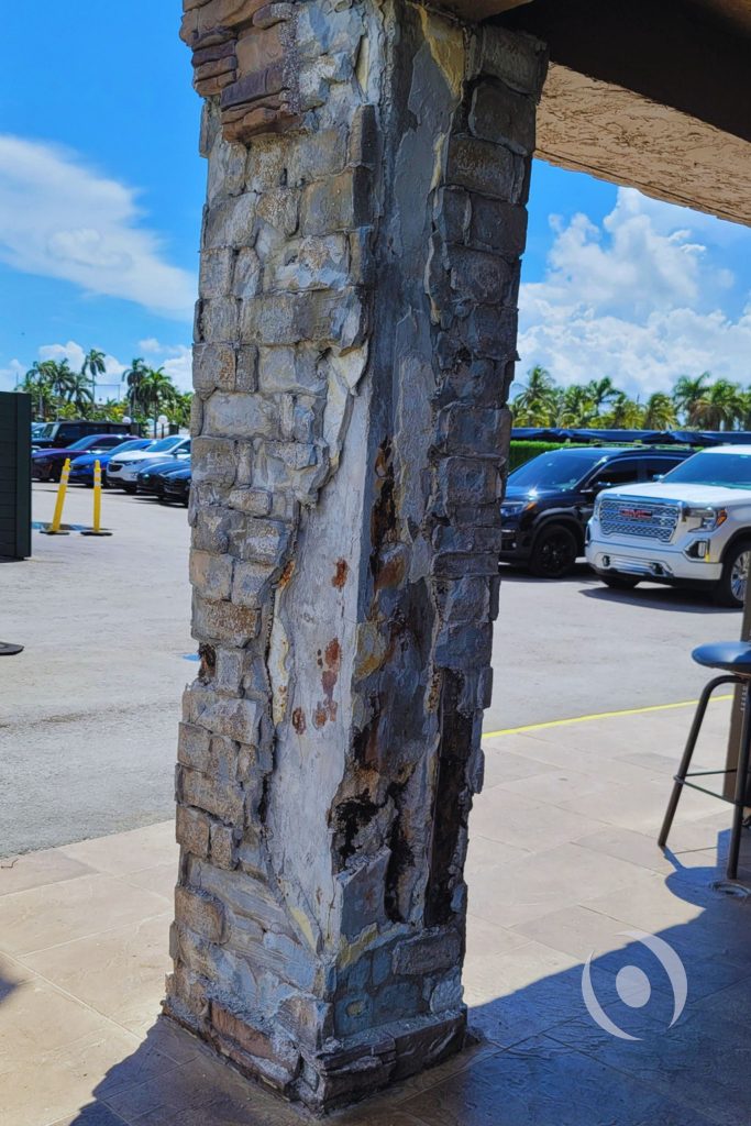 Severely deteriorated exterior concrete column with exposed rebar and spalling on a commercial building in South Florida, flagged during structural engineering assessment by NOHMIS