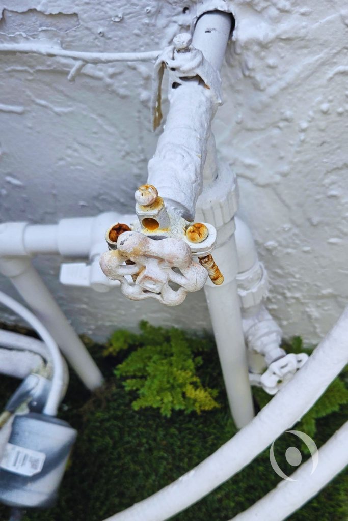 Corroded exterior plumbing valve and pipe connections documented during existing conditions assessment prior to full plumbing redesign for a Boca Raton single-family home renovation
