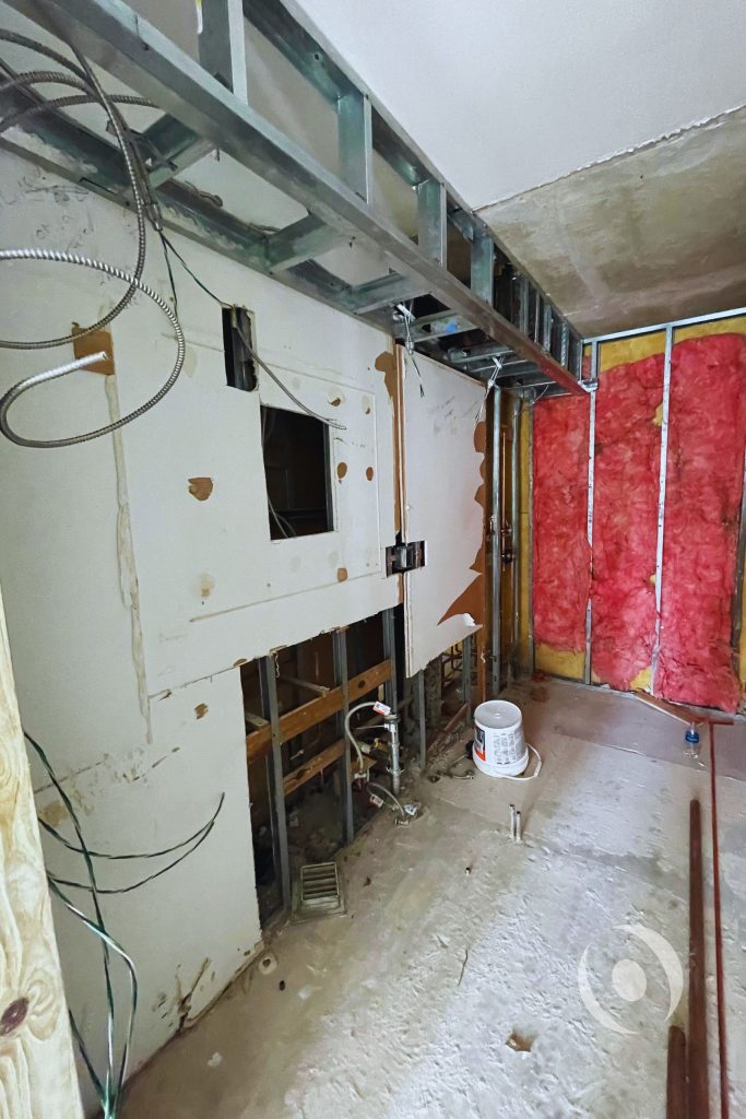 Mid-construction photo showing electrical conduit plumbing rough-in and metal stud framing inside high-rise condominium renovation engineered by NOHMIS in South Florida