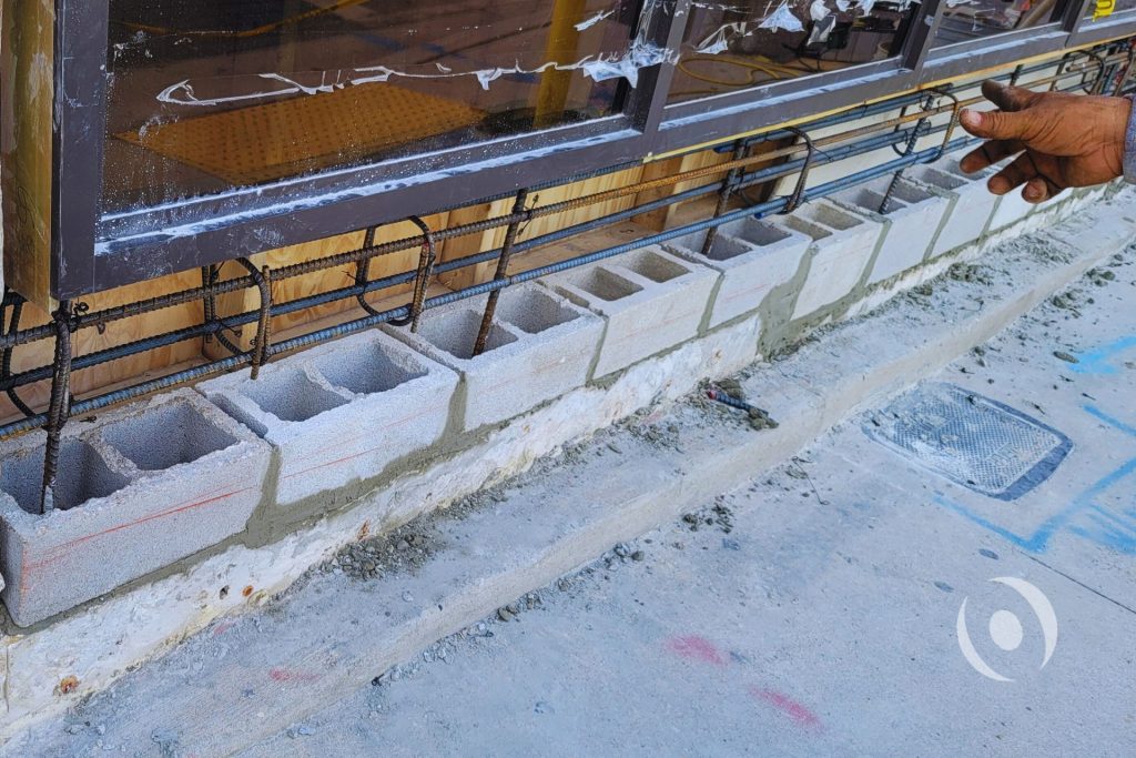 Close-up of new CMU block wall construction with exposed reinforcing steel rebar for tie beam installation during NOHMIS-directed structural repair of commercial building in Hollywood, Florida, per engineer of record permit-ready drawings