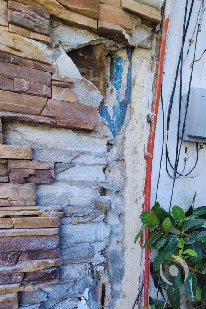 Alt text: Stone masonry facade removed from commercial building exterior revealing years of concealed concrete deterioration and structural damage in Broward County, Florida