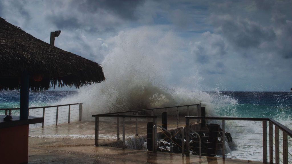 Powerful waves crashing against a waterfront property, illustrating hurricane storm surge, coastal flooding, and seawall risks in South Florida.