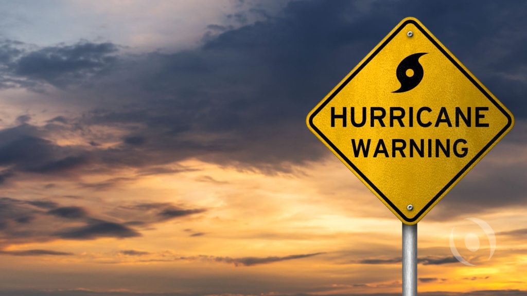 Hurricane warning sign under storm clouds representing hurricane season preparation in South Florida.