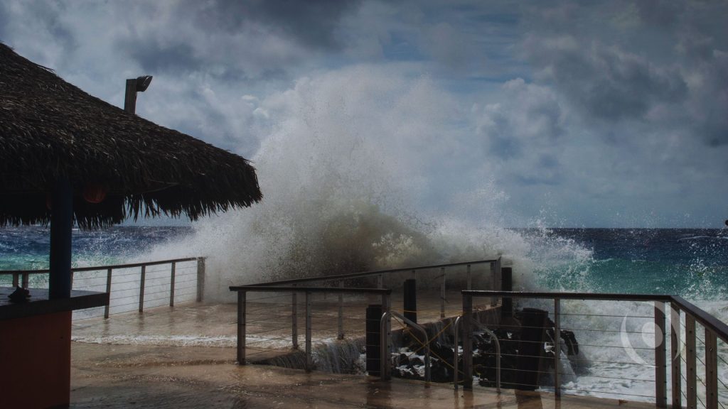 Powerful waves crashing against a waterfront property, illustrating hurricane storm surge, coastal flooding, and seawall risks in South Florida.