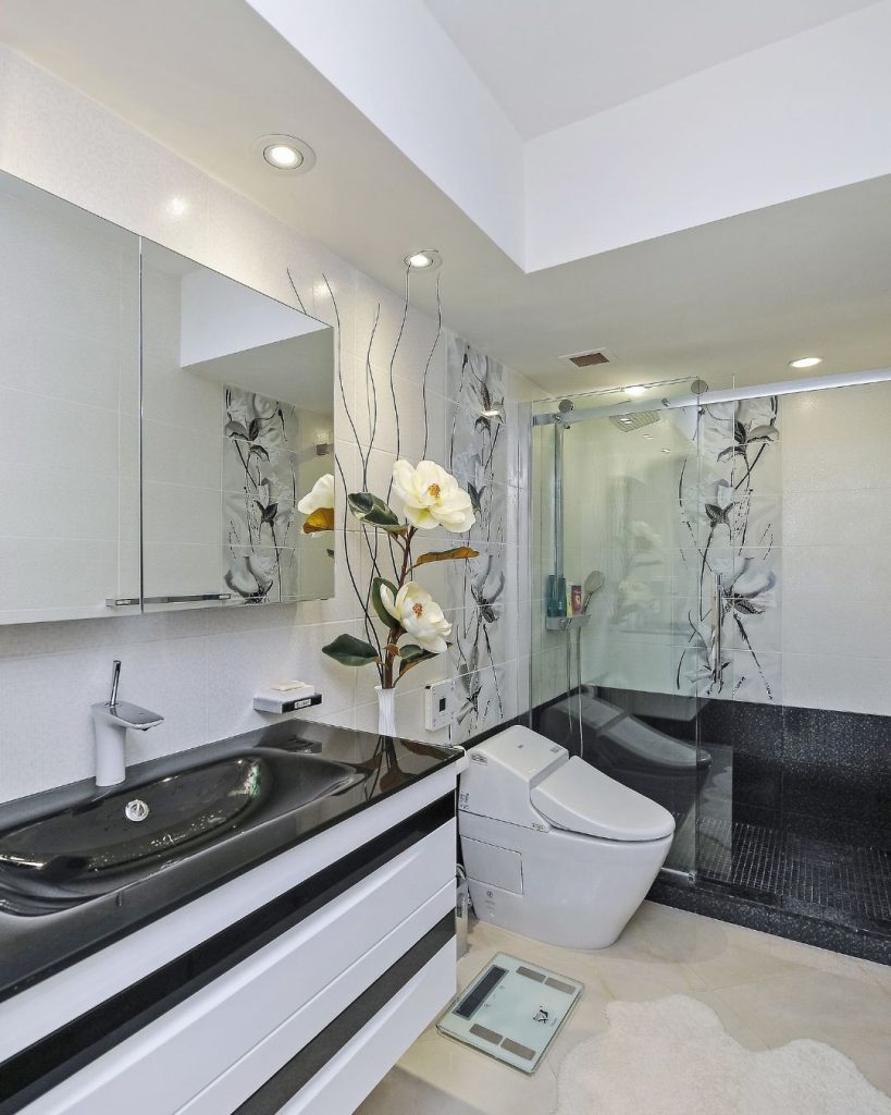 Modern black and white condo bathroom with floating white vanity, smart toilet, and mirrored medicine cabinet