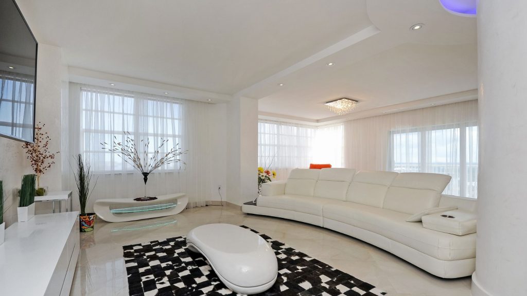 Renovated Hemispheres condo living room in Hallandale Beach with curved white leather sectional and wraparound windows