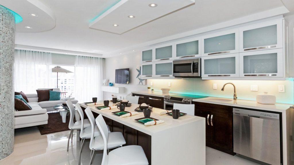 Renovated Hemispheres condo kitchen in Hallandale Beach with white waterfall island and frosted glass cabinets